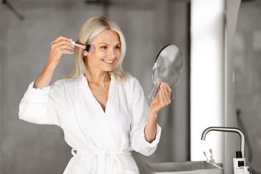 Daily Make Up. Portrait Of Beautiful Senior Woman Applying Blush In Bathroom