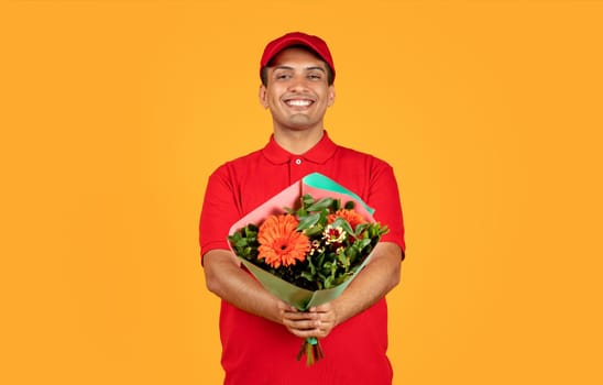 Young Arabic deliveryman presents fresh bouquet of flowers, yellow background