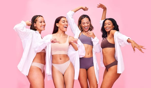 Fun, dancing and women friends in underwear in studio on pink background for beauty or skincare. Lingerie, health and wellness of female model group move for diversity, body positive or inclusion