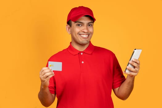 deliveryman using smartphone and credit card on yellow studio background