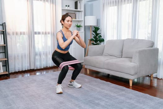 Vigorous energetic woman doing exercise at home with sport band.