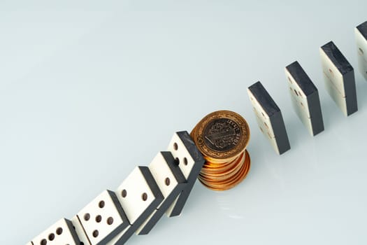 Domino tiles in a row and coins close up. Financial crisis concept