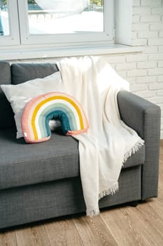 Gray sofa with rainbow pillow near the window