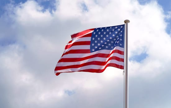 Large American flag waving on flag pole with cloud blue sky. Windy and sunny day with waving stars and striped flag