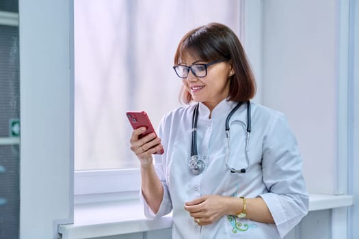 Female doctor with stethoscope with smartphone in her hands in hospital.