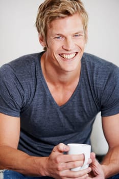 Portrait, smile and coffee with a man in studio on a gray background to drink a caffeine beverage in the morning. Relax, break and mug with a happy young person drinking tea or feeling satisfied