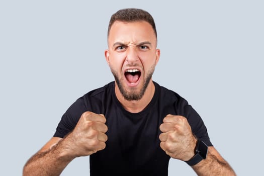 Strong millennial caucasian guy with beard, scream with open mouth, with fists