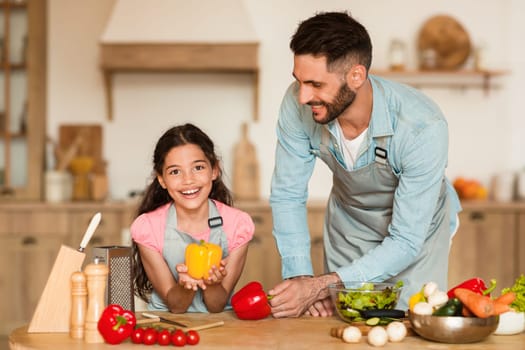 Father and daughter with bell pepper, cooking together
