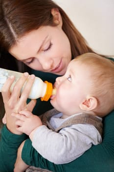 Woman, holding and baby with bottle for feeding in home for growth, child development or hunger. Mother, son and bond by looking at boy for formula, food or milestone in nutrition, health or diet
