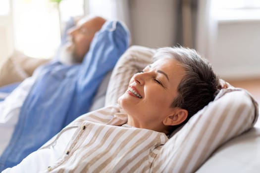 Smiling Senior Couple Resting Together On Comfortable Sofa At Home