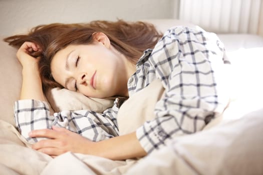 Woman, sleeping and tired for fatigue in bedroom with nap in morning for insomnia. Person, girl or lying down for rest, peace or calm for blanket in comfort in home for health, wellness or exhaustion