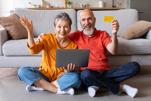 E-banking Concept. Excited Senior Spouses With Laptop And Credit Card At Home