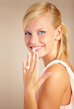 Woman, happy and wedding ring in studio portrait with smile for proposal, engagement or commitment by background. Girl, model and jewelry for marriage, diamond and metal for celebration at ceremony