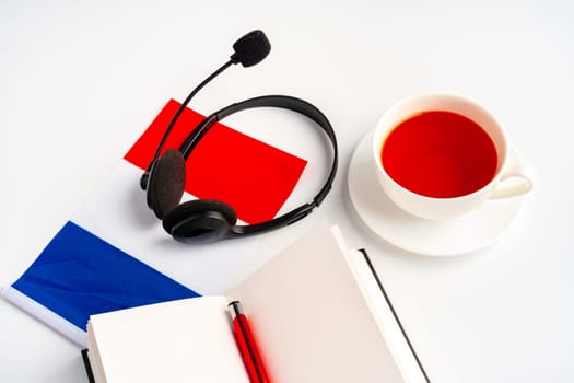 Notepad with France flag and headphones on white background. French language audio courses educational concept