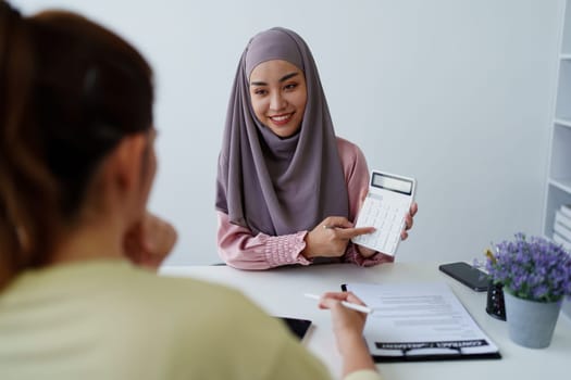 A female Muslim bank employee, making an agreement on a residential loan with a customer.