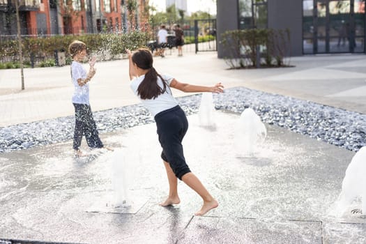 life of children in a modern city - little girl having fun with fountains