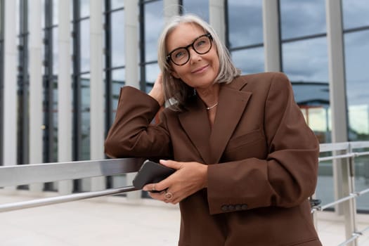 beautiful gray-haired successful mature business woman enjoying freelancing outdoors