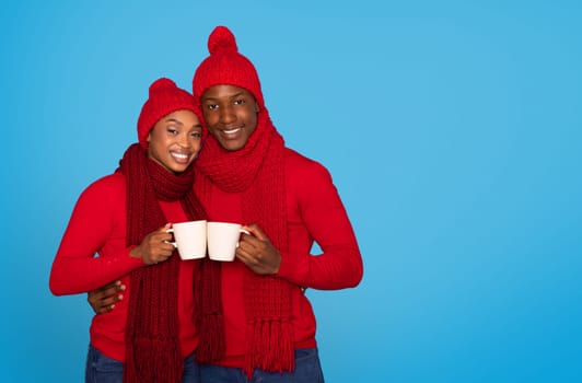 Black Couple In Knitwear Holding Coffee Cups Over Blue Background