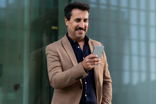 Happy handsome mature businessman using cell phone outdoors