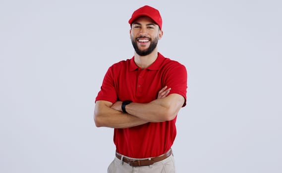 Happy man, portrait and professional delivery guy with arms crossed in confidence against a gray studio background. Male person, model or courier worker smile with red hat for service on mockup space