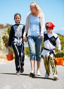 Going trick or treating. Children in costume going treat or treating with their mom.