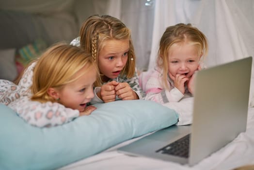 Its their favourite cartoon to watch before bed. three little sisters watching something on a laptop before bedtime.