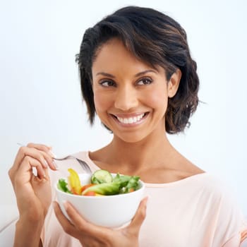 Smile, health and woman with a salad in studio with vegetables for wellness, organic or diet. Happy, nutrition and young female person from Mexico eating healthy meal with produce by white background
