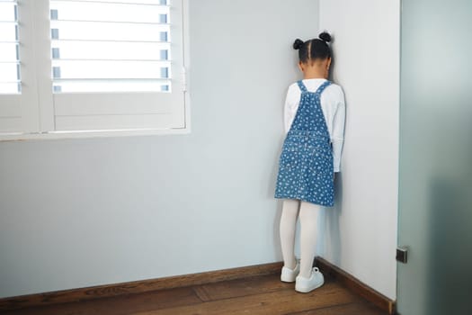 Hurt little tender heart. an unrecognizable little girl facing the wall and as punishment in a room at home.