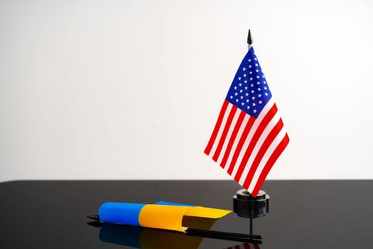 Flags of USA and Ukraine on black table against white background