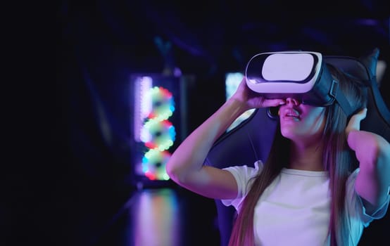 Girl gamer putting on a VR glasses in neon lighting