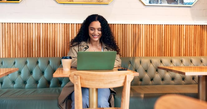 Happy woman in coffee shop, typing on laptop and remote work, reading email or writing blog, article or search on technology. Computer, freelancer or copywriting in cafe, store or restaurant at table