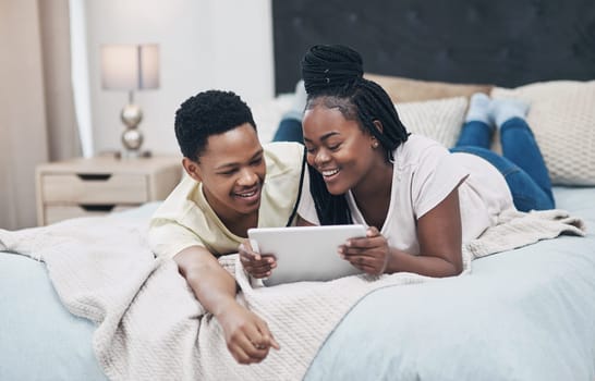 Dates can be just as fun during lockdown. a young couple using a digital tablet while relaxing on their bed at home.