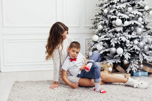 Mom with son at christmas tree with gifts garland winter