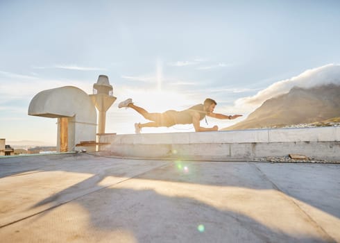 It time for you discover just how capable you are. a man doing a single-arm plank while on a rooftop.