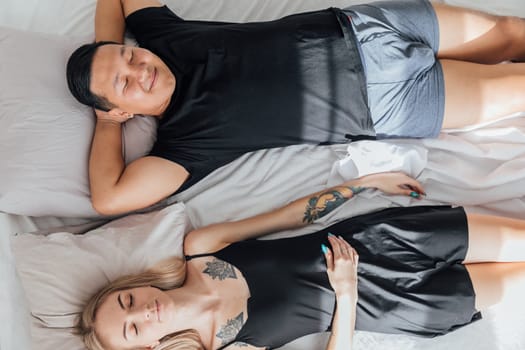 Husband and wife sleeping together in bed in the morning