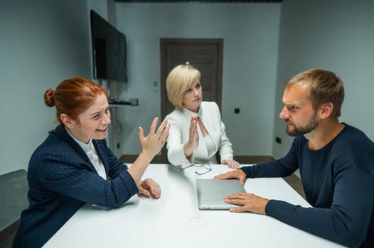 Blond, red-haired woman and bearded man in suits in the office. Business people are swearing during negotiations in the conference room.