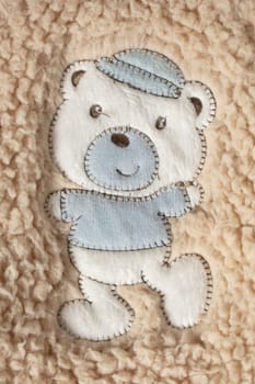 On the fur is a fabric application of a cute teddy bear.