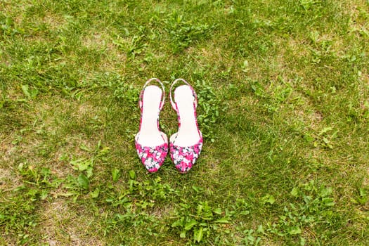 Shoes of a woman on green grass. Summer holiday concept, daylight