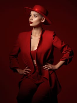 Vision, fashion and a woman thinking on a red studio background for elegant or trendy style. Aesthetic, future and beauty with a young female model standing hands on hips while looking edgy or classy