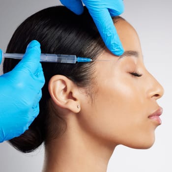Closeup of a gorgeous mixed race woman getting botox filler. Hispanic model getting filler to reduce wrinkles against a grey copyspace background in a studio
