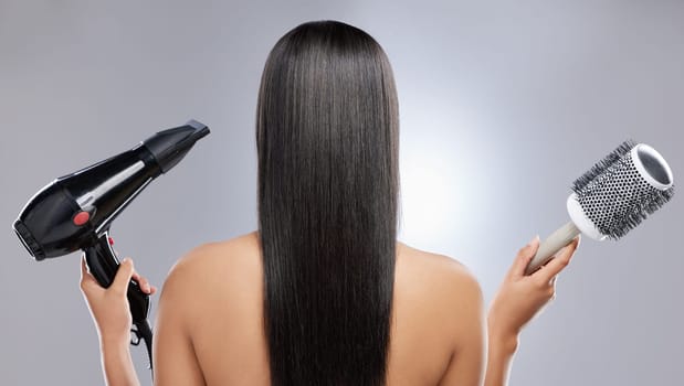 Volume or no volume. Rearview shot of a woman with sleek hair holding a hairdryer and blow-dry brush.
