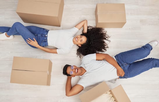 New beginnings loading. a young couple lying on the floor while unpacking boxes in their new house.