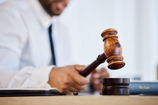 Hand, gavel and a man judge in court for order at a verdict in a criminal case or trial closeup. Justice, law or legal with a magistrate hammer in a courtroom for a hearing of evidence or legislation