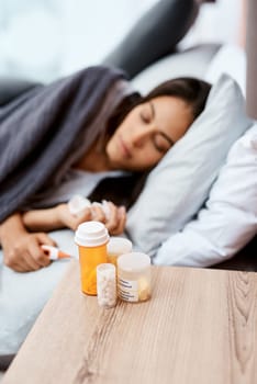 Every pill for every symptom possible. a young woman recovering from an illness in bed at home.