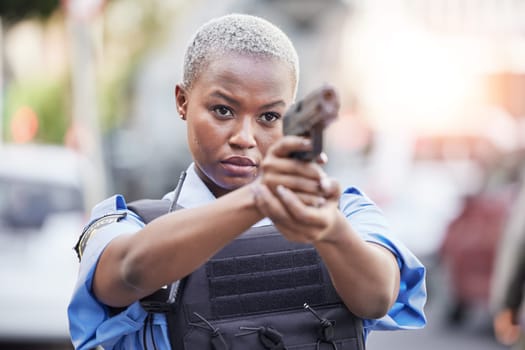 Gun, serious and female police officer in the city for an arrest to stop crime in a street. Upset, young and African woman security guard with pistol for safety, authority and law enforcement in town