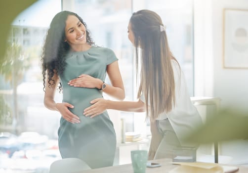 Thank you for supporting my at work through my pregnancy. a businesswoman touching her colleagues pregnant belly in an office.