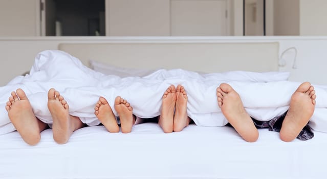 Family, feet and bed with blanket for sleeping, relaxing or rest together with calm and peace in home. People, parents and children with duvet in morning on vacation, holiday or hotel on weekend