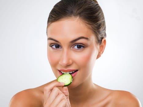 Good food wont go to waste. Portrait of a gorgeous young woman eating a slice of cucumber.