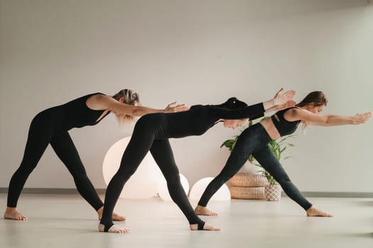 A group of girls in black doing yoga poses indoors. Women are engaged in fitness