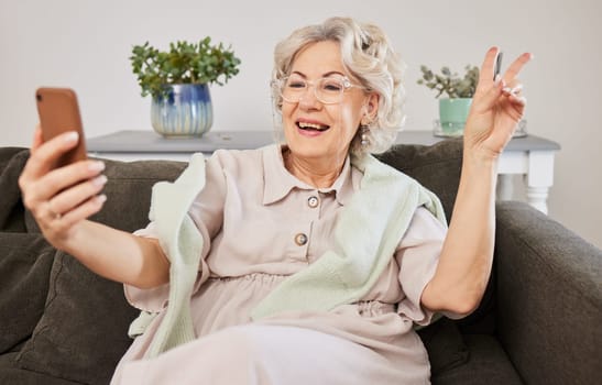 Selfie, peace and a senior woman posing on a sofa in the living room of her home during retirement. Social media, profile picture and hand gesture with a happy mature female person in her house